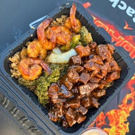 Steak bites and shrimp with broccoli, onion and fried rice, sauce cup on the side